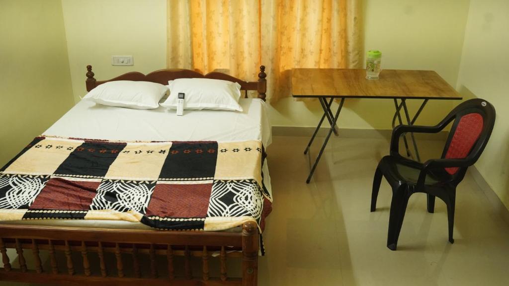 a bedroom with a bed and a table and a table and chair at SS Family Villa in Varkala
