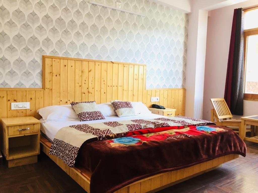 een slaapkamer met een groot bed met een houten hoofdeinde bij HOTEL CORNER RETREAT BnB in Manāli