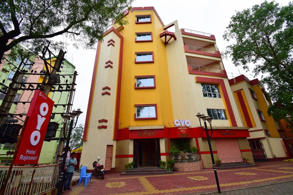 a yellow and red building with people standing around it at OYO Hotel Rajeswari in Rupnārāyanpur