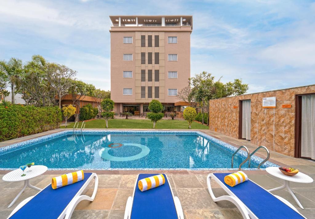 una piscina con 2 tumbonas y un hotel en Zone Connect by The Park,Udaipur, en Udaipur