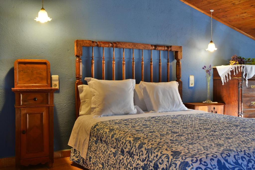 een slaapkamer met een groot bed met een houten hoofdeinde bij Les Velles Escoles in Les Irles