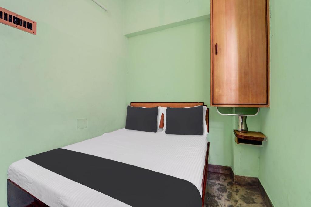 a bedroom with a bed and a wooden cabinet at OYO Rainbow Stays in Tiruchirappalli