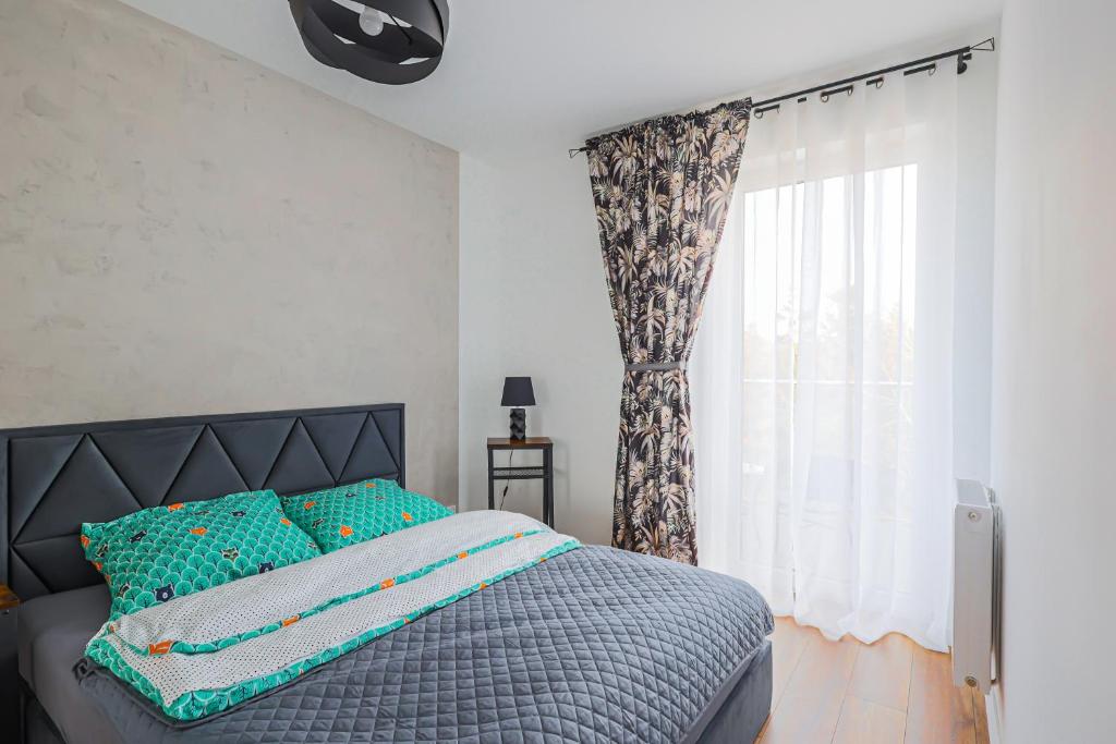 a bedroom with a bed with blue pillows and a window at Apartament 32 in Gąski