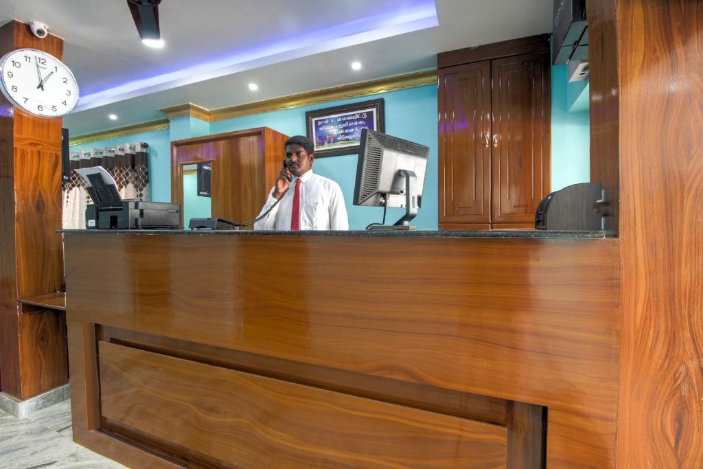 a man talking on a cell phone at a cash counter at Collection O Hotel Jaisas Paradise in Agastīswaram