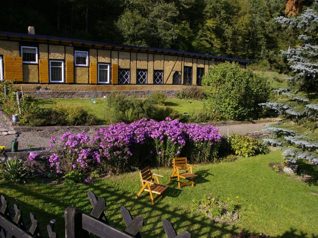 a garden with two benches and flowers in front of a building at Idyllic studio apartment near Kaifenheim and near the forest in Kaifenheim