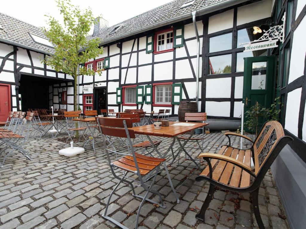 シュライデンにあるNostalgic apartment in the Eifel regionの建物の前にテーブルと椅子付きのパティオ