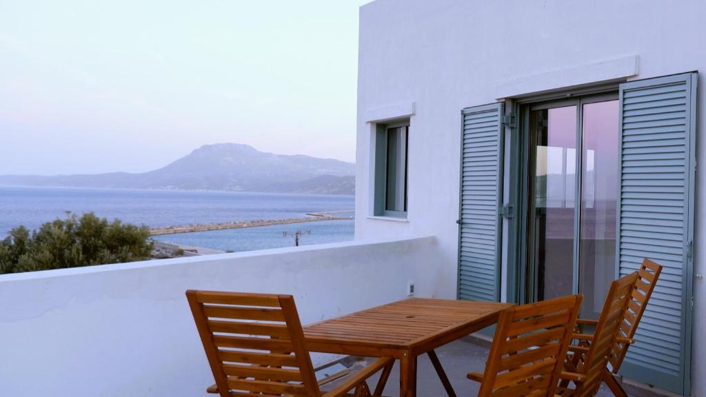 a wooden table and chairs on a balcony with the ocean at Sterna Suites in Paralía Kímis