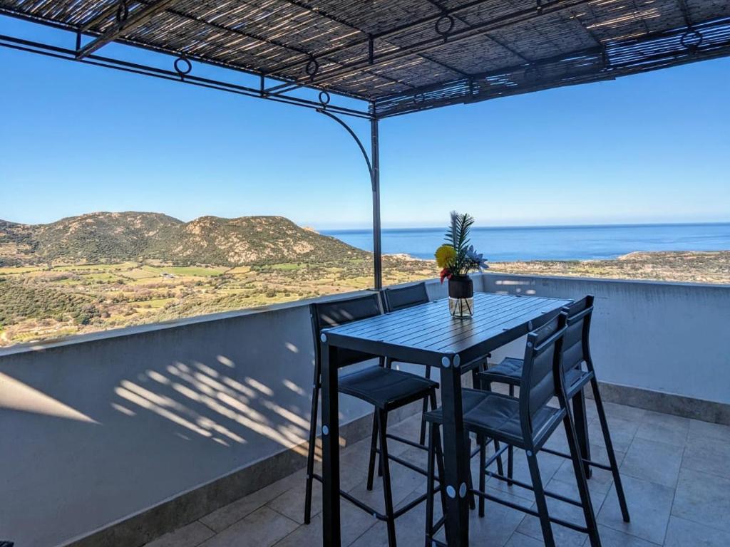 un tavolo e sedie su un balcone con vista sull'oceano di A Casa Praoli - Coin de paradis vue mer ad Aregno