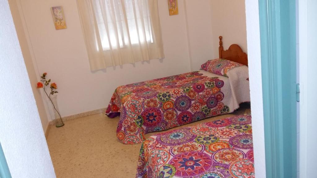 a bedroom with two beds and a window at Pensión Campomar in Cartaya