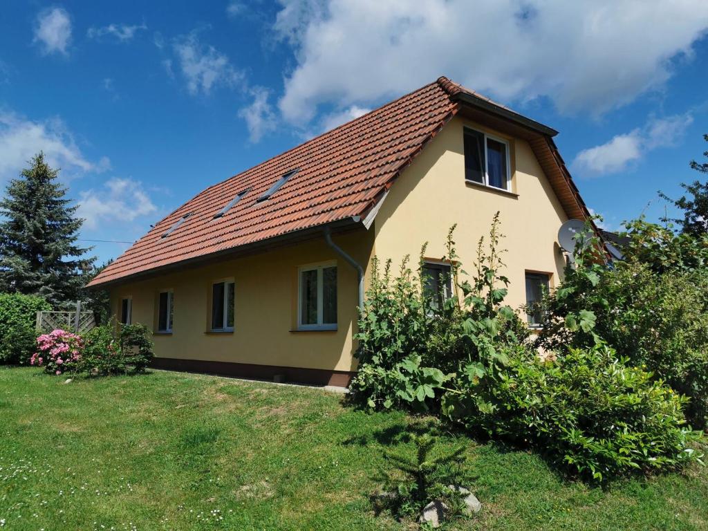 una pequeña casa amarilla con techo rojo en Spacious appartment in Wilhelmshof near Lake en Wilhelmshof