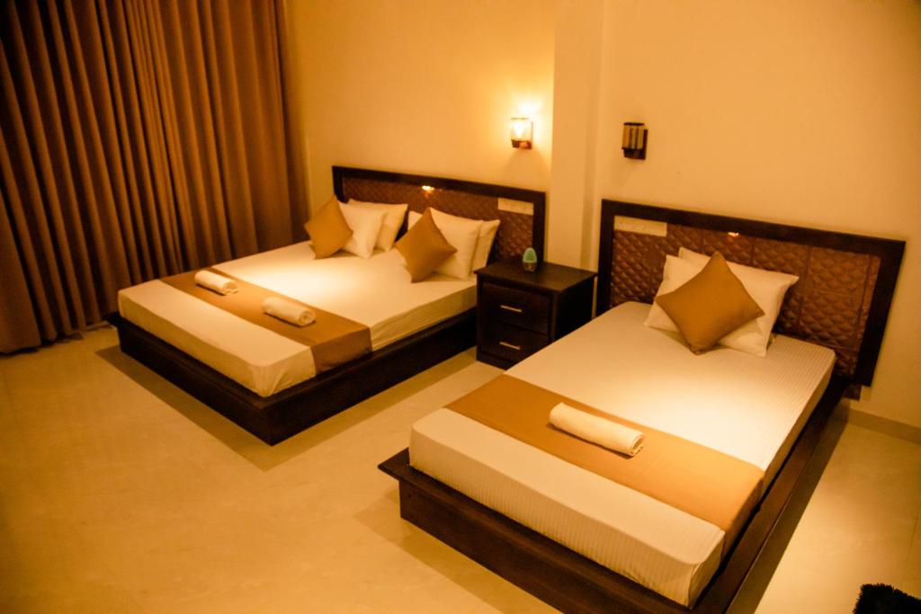 a hotel room with two beds and a table at Sharta Yala in Tissamaharama
