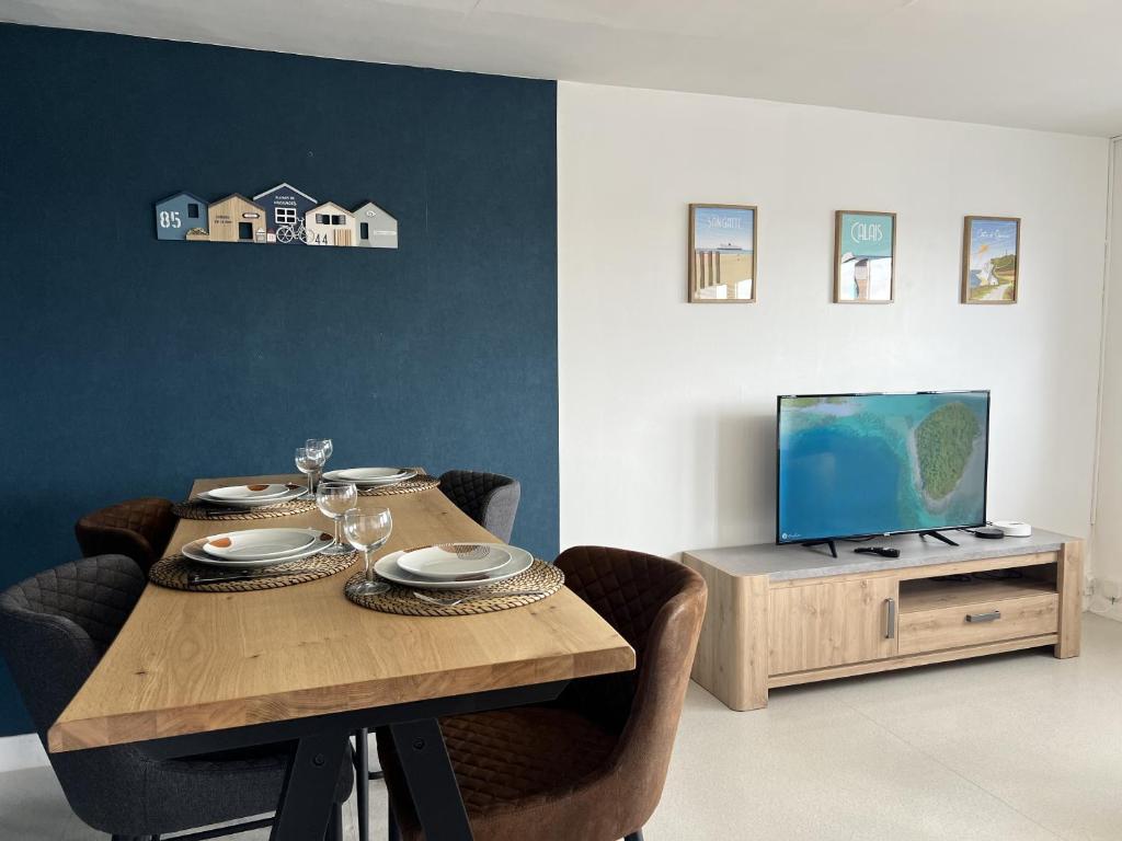 une salle à manger avec une table et une télévision dans l'établissement Le Phare, à Calais