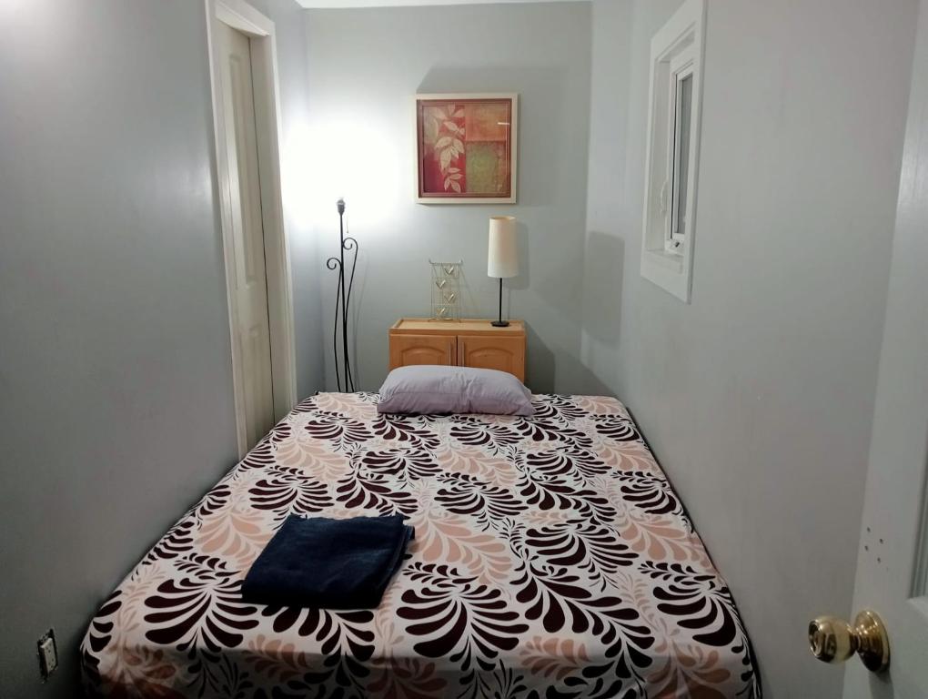 a bedroom with a bed with a black and white blanket at Small Cozy Private Room For 1 or 2 Travellers in a Great Location (King George Boulevard, Surrey) in Surrey