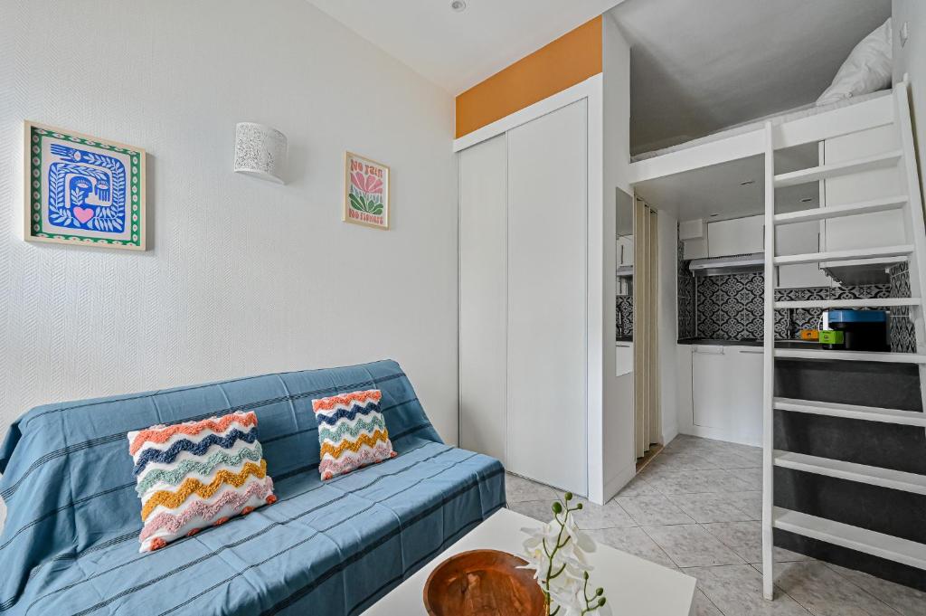 - un salon avec un canapé bleu et des lits superposés dans l'établissement Le Saisonnier - Charme & Confort - Porte de Paris, à Saint-Ouen