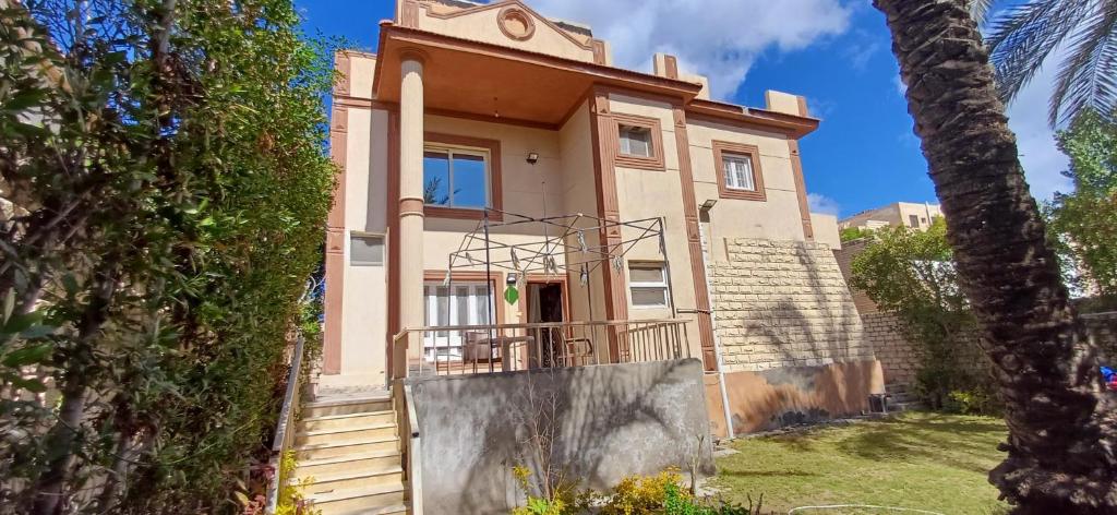 una casa con una escalera delante de ella en Lovely 5Bedroom Villa -Compound - Swimming Pool at Green Oasis Resort, en ‘Izbat as Sarāḩnah