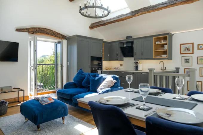 Naze View Barn - Cosy, with all mod cons في Whaley Bridge: غرفة معيشة مع أريكة زرقاء وطاولة