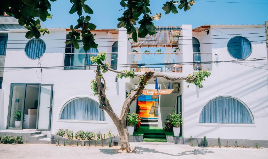 un edificio bianco con un albero di fronte di Thuyền Xưa Homestay Đảo Phú Quý a Cu Lao Thu