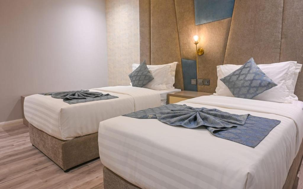 twee bedden in een hotelkamer met handdoeken erop bij جاردن إيست هوتيل-الخبر in Raʼs Munaysif