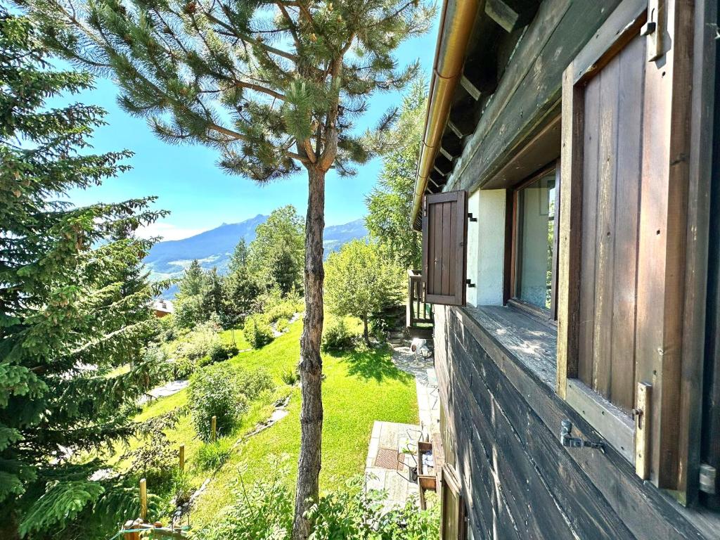 a house with a window and a tree on the side at ComeCasa La Magdeleine 2 Bedrooms Chalet in La Magdeleine