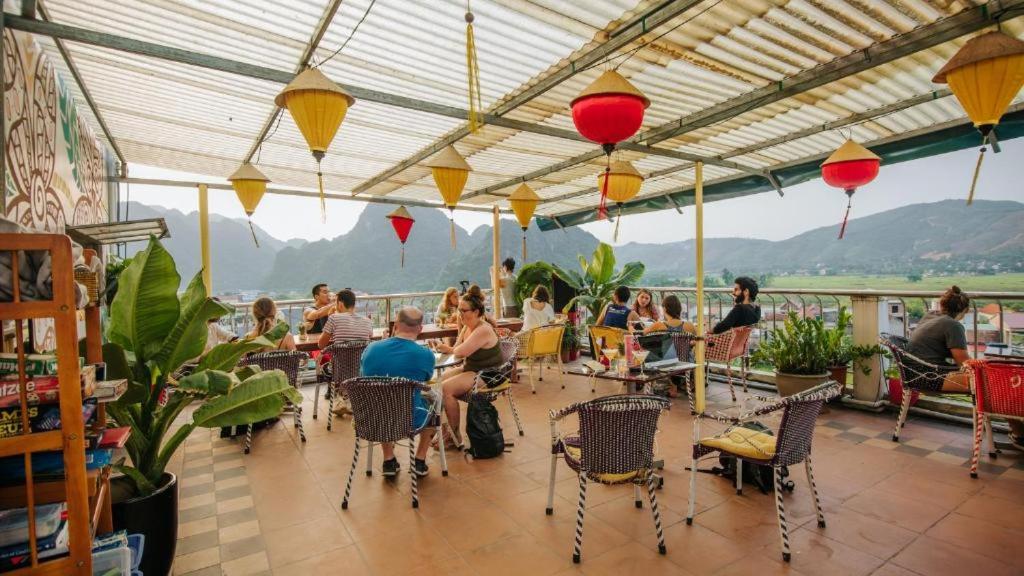 Phong Nha Jasmine Hostel & Roof Top Bar في فونغ نها: مجموعة من الناس يجلسون على الطاولات في الفناء