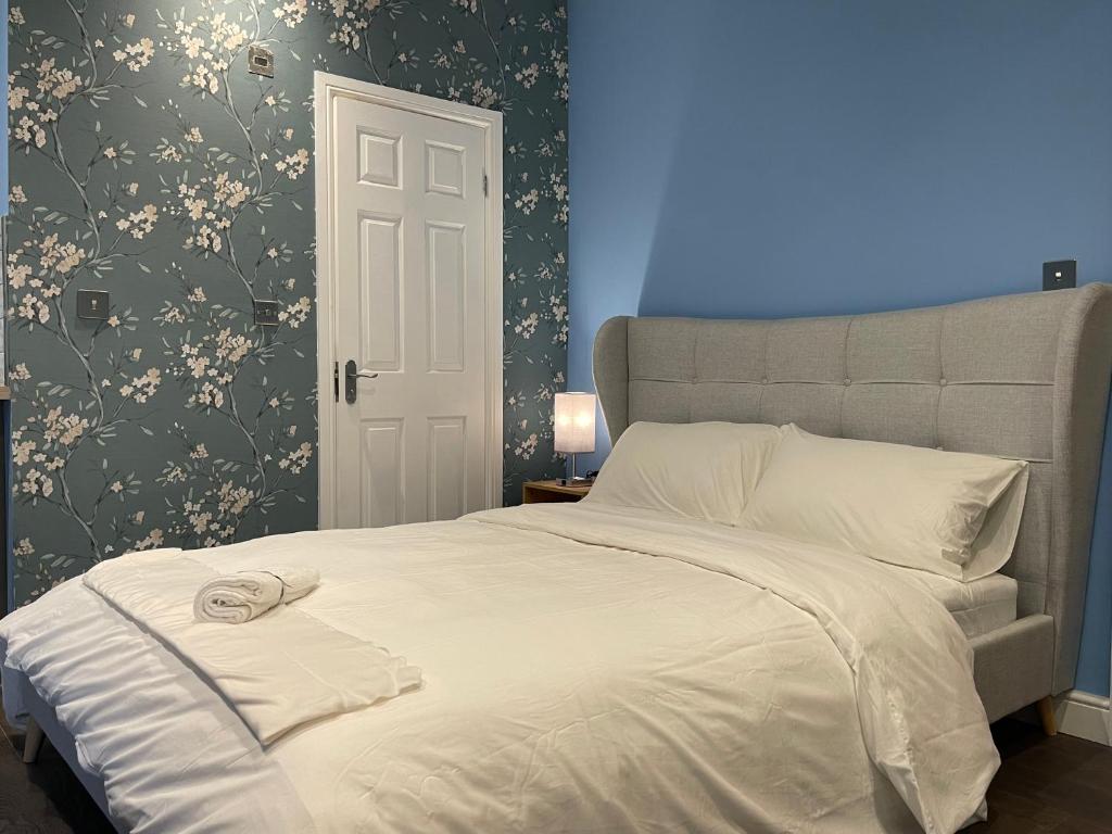 a bedroom with a large white bed with a blue wall at Luxurious Restful Studio Flat, Less Than 30 Mins From Centre! in London