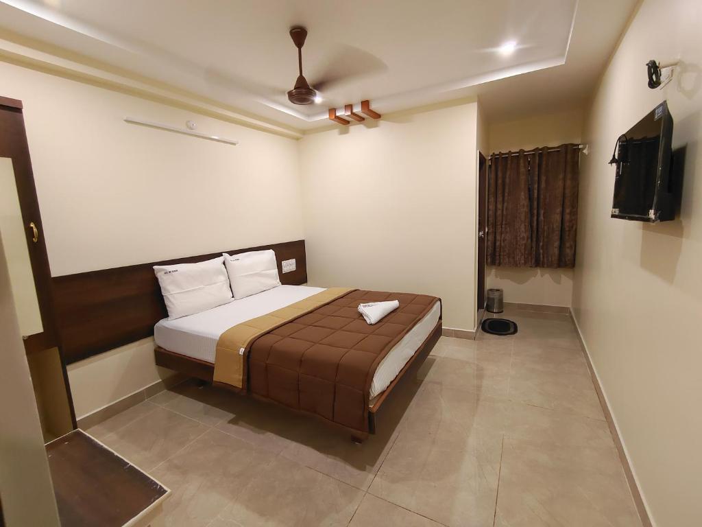 1 dormitorio con 1 cama y TV en HOTEL DKR GRAND, en Tirupati