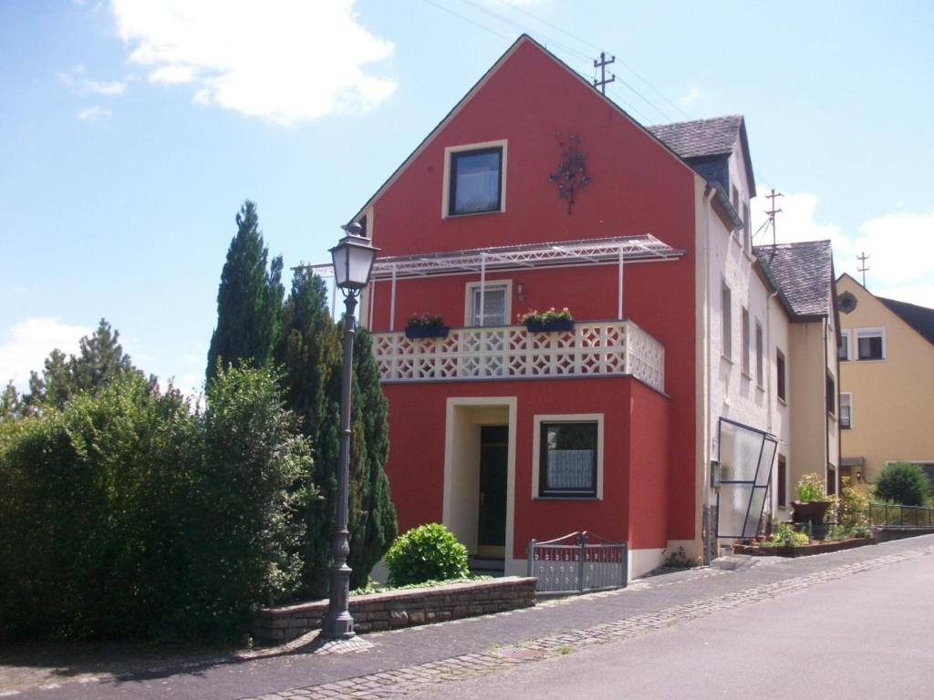 ein rotes Haus mit Balkon auf einer Straße in der Unterkunft Comfortable Holiday Home near Vineyards in Bremm in Bremm