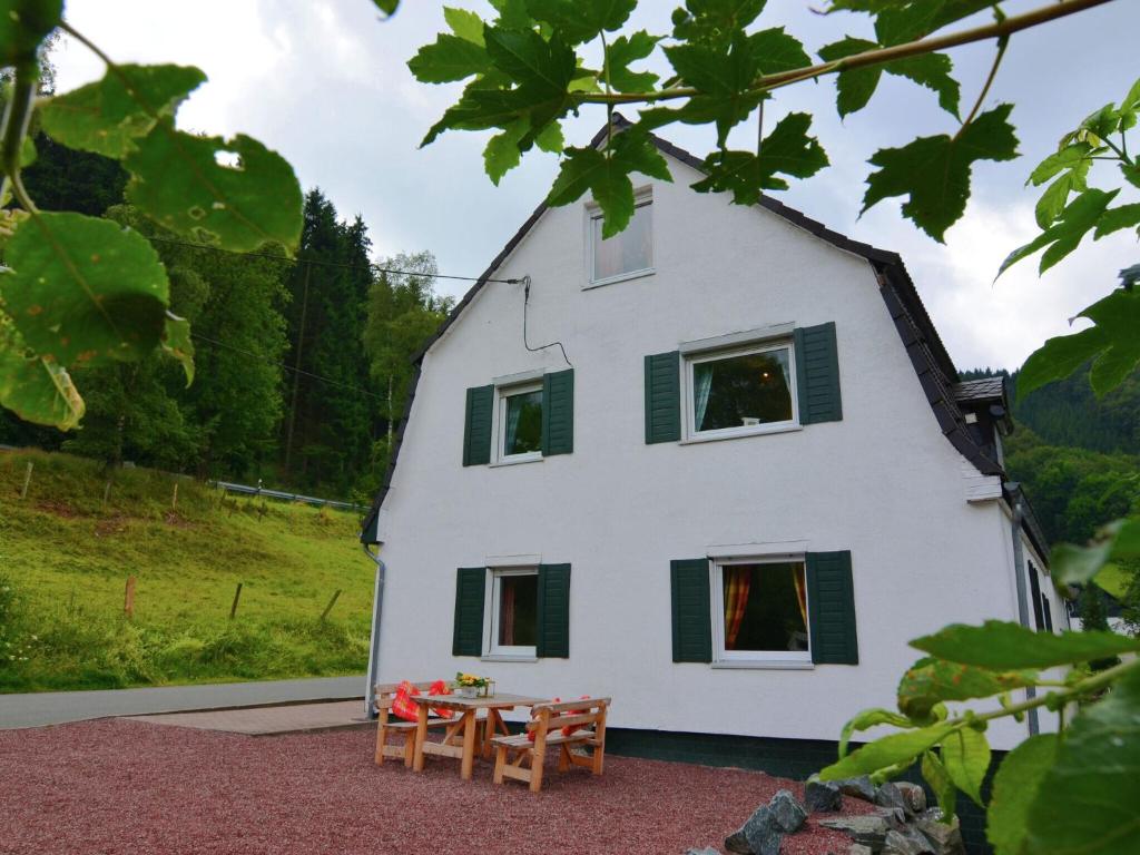 a white house with green shuttered windows and a table at Wonderful Apartment in Elpe with Garden in Elpe