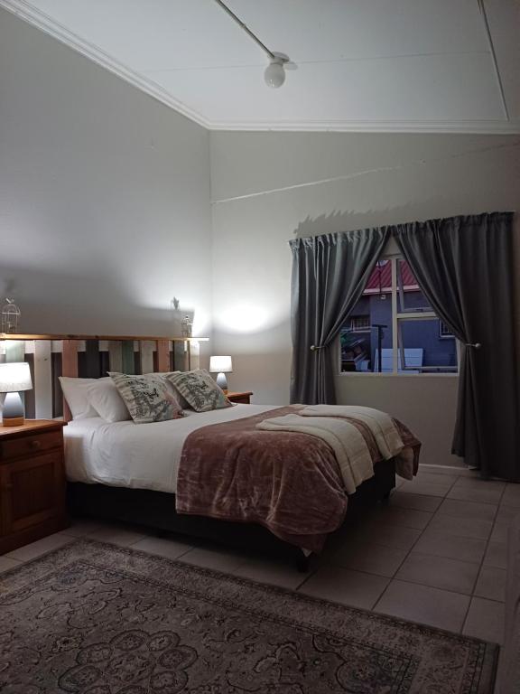 a bedroom with a large bed and a window at Winemaker's Rest in Oudtshoorn