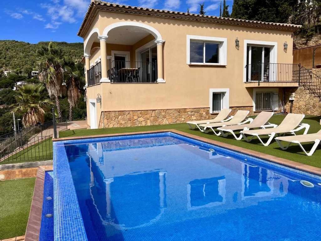 a villa with a swimming pool in front of a house at Casa Mas Ambros con piscina desbordante in Calonge
