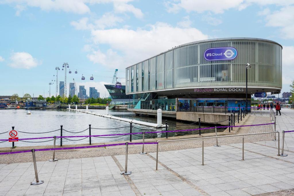 a large building next to a body of water at Heads on Bed- London Excel Royal Victoria Dock O2 in London