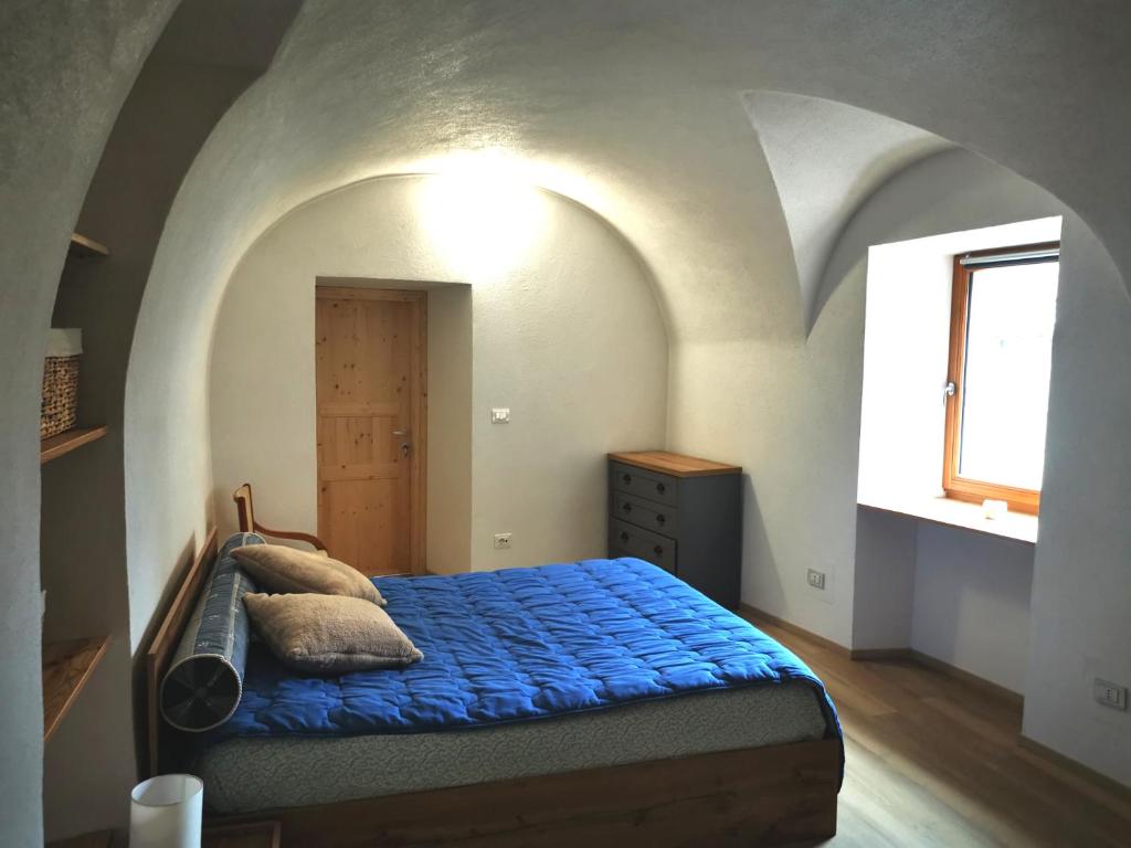 1 dormitorio con cama con sábanas azules y ventana en Appartamento sci & laghi "Tre Fontane", en Tione di Trento