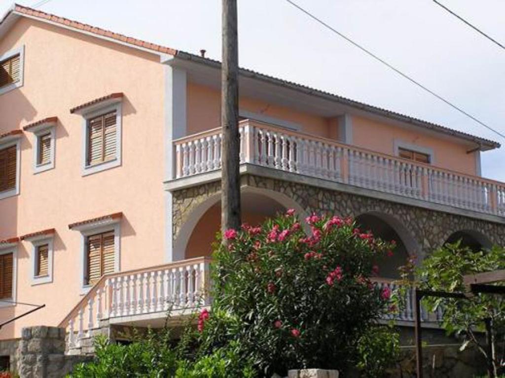 un grand bâtiment rose avec un balcon. dans l'établissement Apartments Petrovic, à Šilo