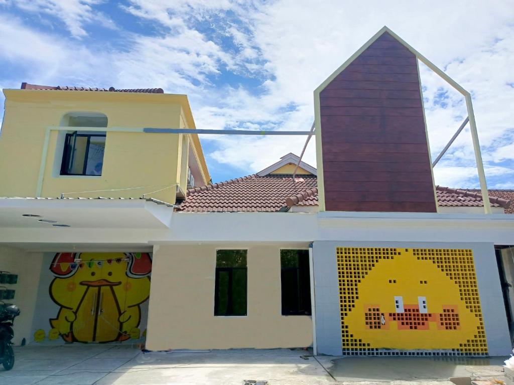 a house with two paintings on the side of it at Bebek Kuning Residence in Blimbing