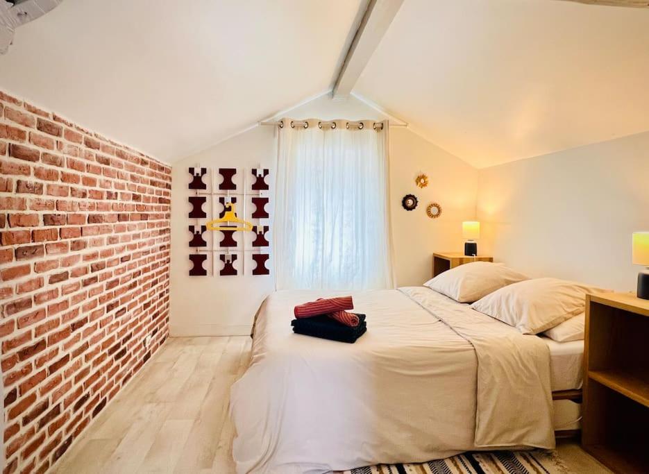 ein Schlafzimmer mit einem weißen Bett und einer Ziegelwand in der Unterkunft Cosy townhouse near the forest and RER in Saint-Germain-en-Laye