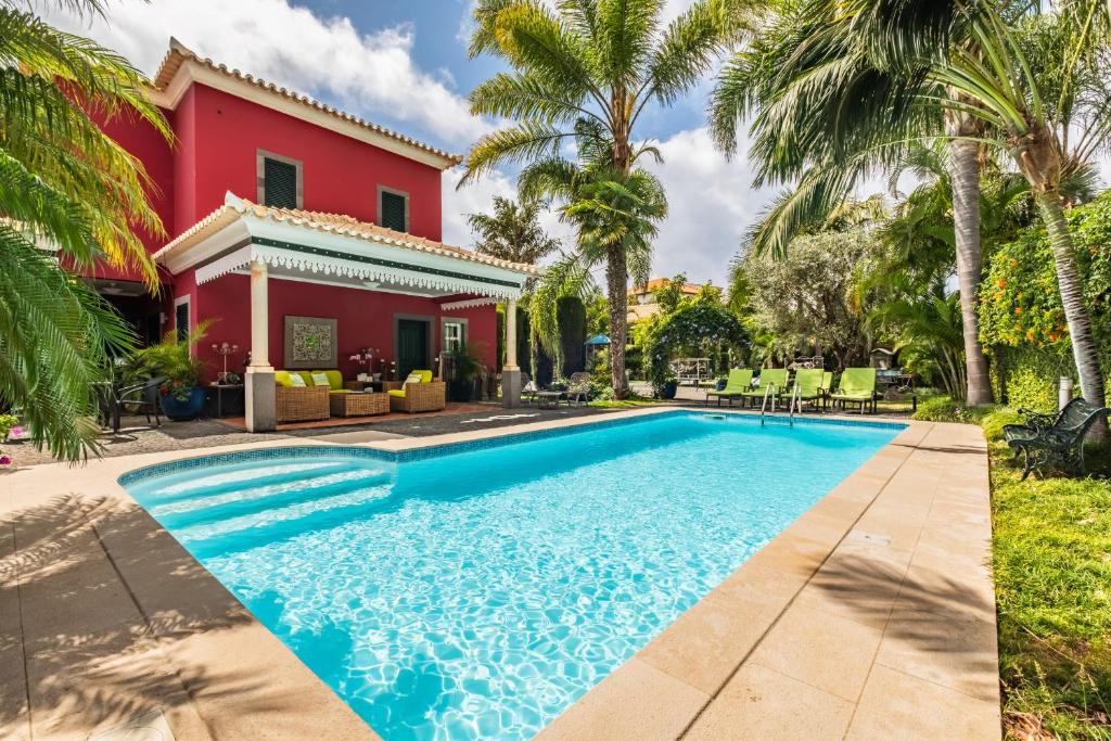 a swimming pool in front of a house with palm trees at Quinta da Tia Briosa by Madeira Sun Travel in Ponta do Sol