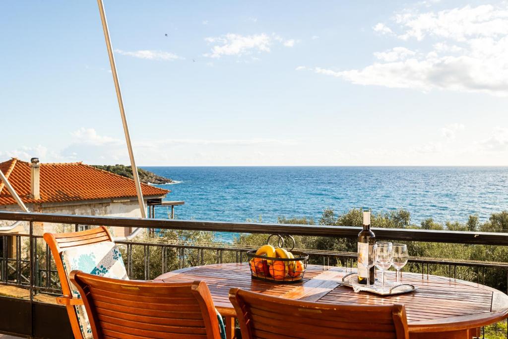 a table with a bowl of fruit on a balcony with the ocean at Sunset Serenity - Kardamili Seaside Getaway in Kardamili