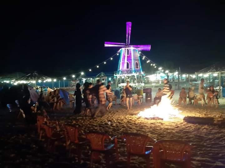a group of people standing around a fire on the beach at night at Nhà nghỉ Biển Xanh in Hộ Vệ