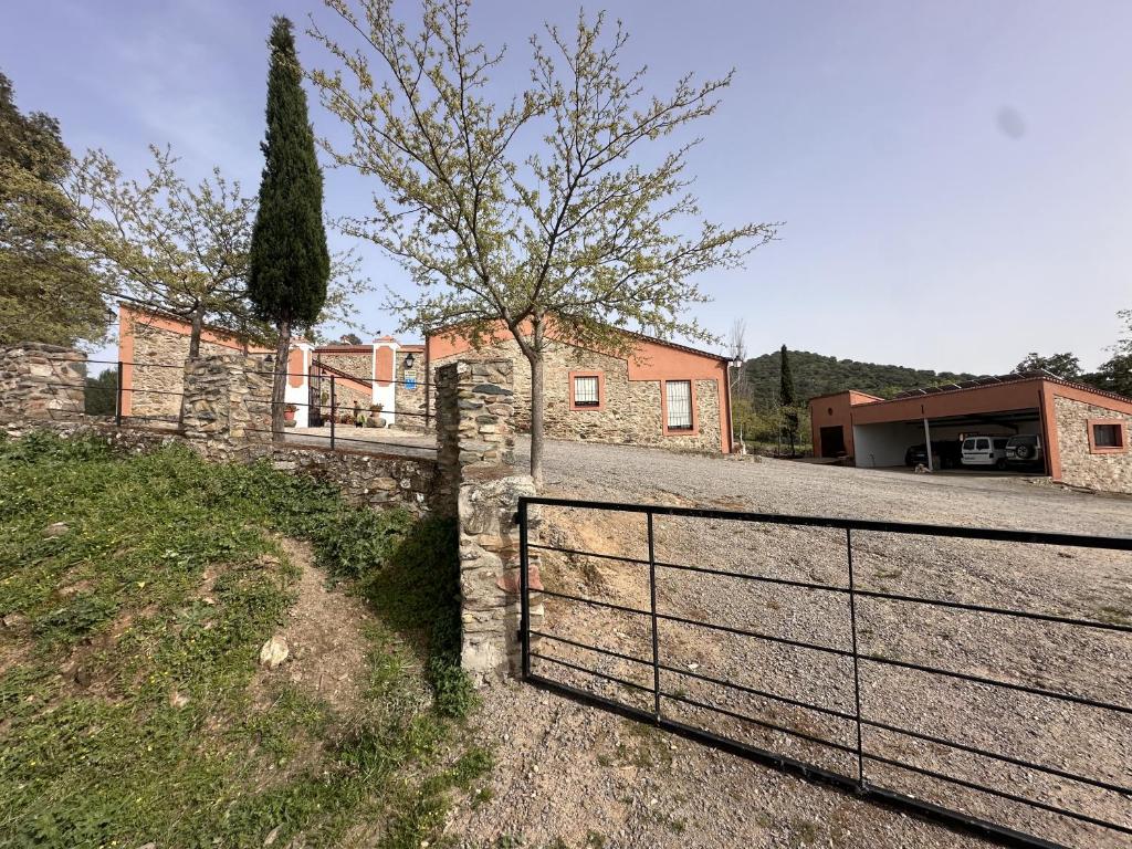 uma cerca em frente a uma casa com uma árvore em Casa rural en Badajoz em Jerez de los Caballeros