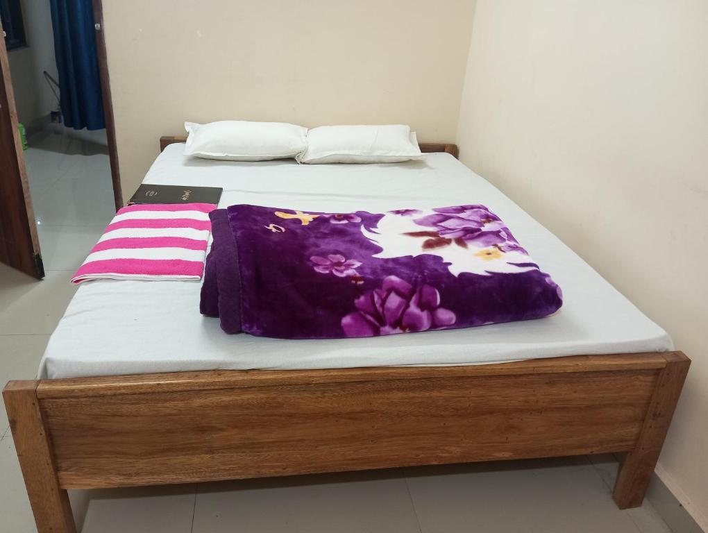a bed with a purple blanket on top of it at ALPHA Hotel in Imphal