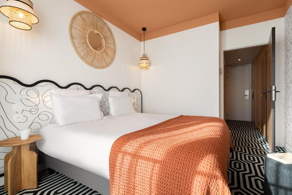 a bedroom with a large white bed with an orange blanket at Albert 1er in Nice