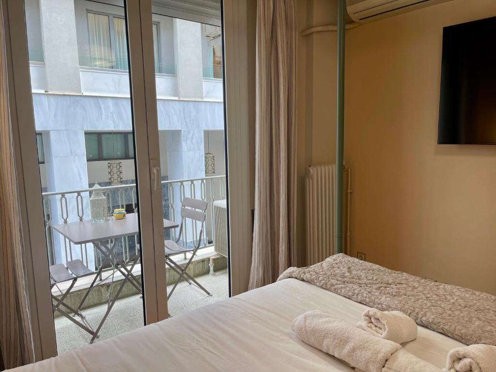 1 dormitorio con 1 cama y balcón con mesa en Athens Spirit Apartment en Athens