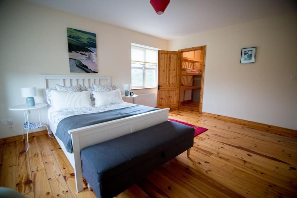 Schlafzimmer mit einem Bett und Holzboden in der Unterkunft *Spacious Irish Cottage* in Fanore