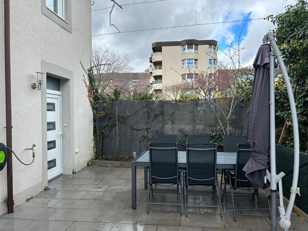 un patio con mesa, sillas y sombrilla en Appartement Cormondrèche, en Neuchâtel