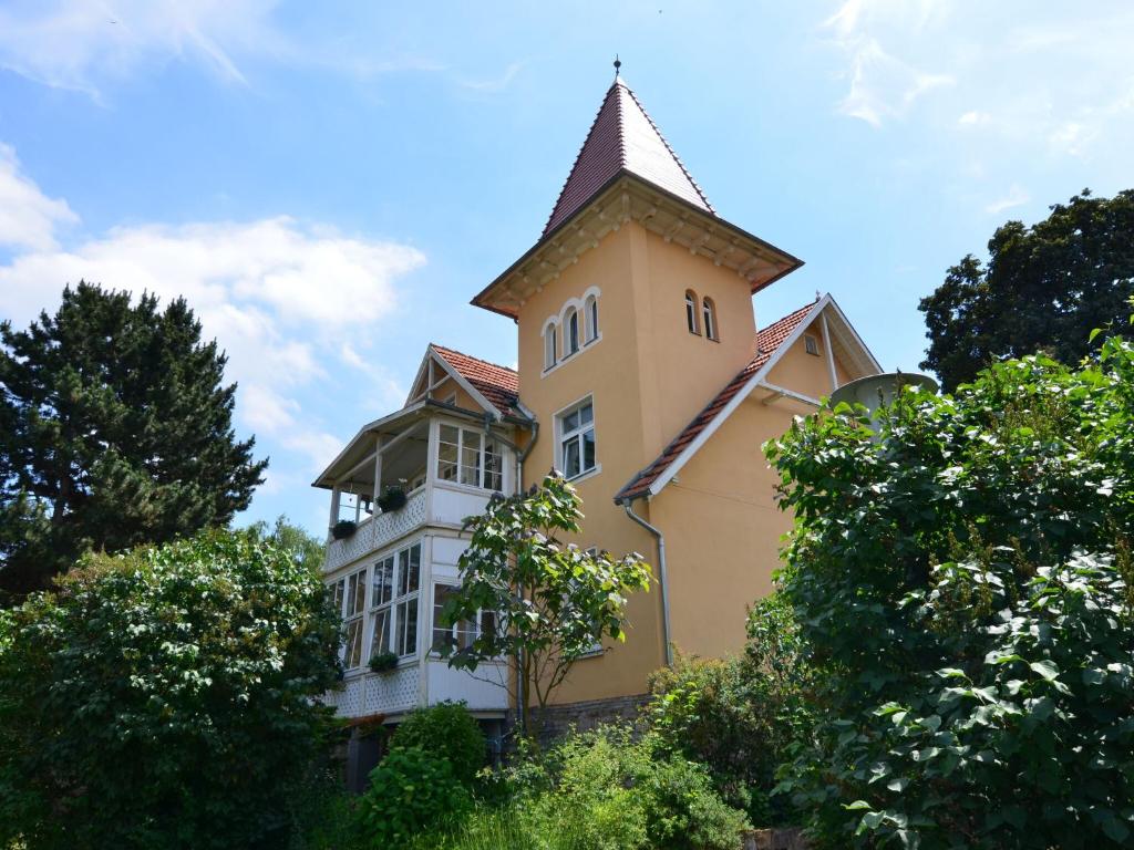 ein gelbes Gebäude mit einem Turm darüber in der Unterkunft Modern apartment in a listed villa with beautiful view from balcony in Bad Suderode