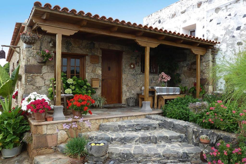 een stenen huis met een veranda met bloemen ervoor bij holiday home Caserio Lomo Arriba Casa Tia Benigna Vera de Erques in Vera de Erque