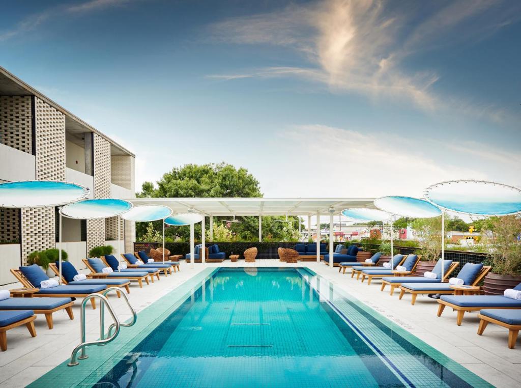 a swimming pool with lounge chairs and umbrellas at South Congress Hotel in Austin