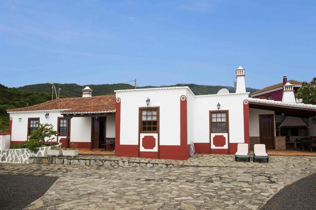 biało-czerwony budynek z dwoma krzesłami z przodu w obiekcie Holiday Home Puntallana - SPC02018-F w mieście Puntallana