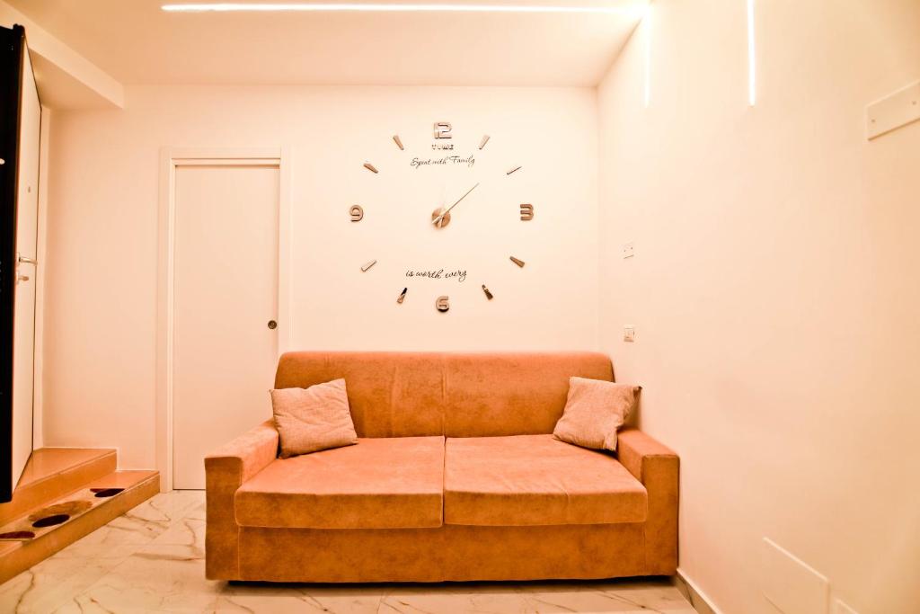 um sofá num quarto com um relógio na parede em La casa di anna em Nápoles