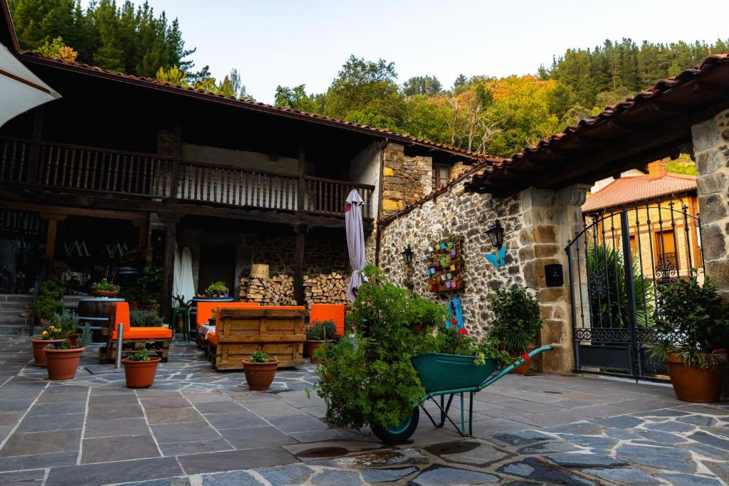 un patio con sillas naranjas y una carretilla verde en Posada Villa Matilde, en Cillorigo de Liébana